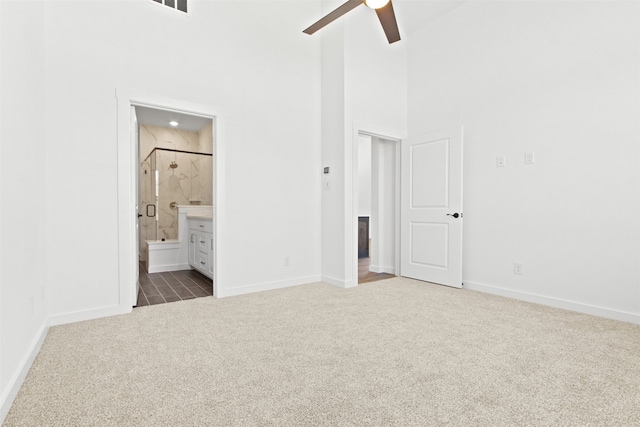 unfurnished bedroom with a high ceiling, carpet, ceiling fan, and ensuite bathroom