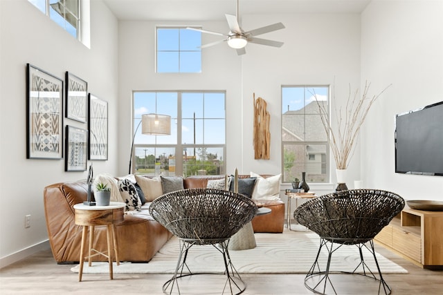 sitting room featuring ceiling fan, light hardwood / wood-style floors, and a high ceiling