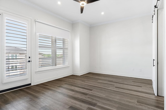 empty room featuring a barn door, dark hardwood / wood-style floors, ceiling fan, and ornamental molding