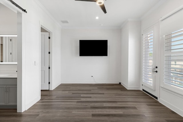 unfurnished bedroom featuring ornamental molding, a barn door, ceiling fan, and hardwood / wood-style floors