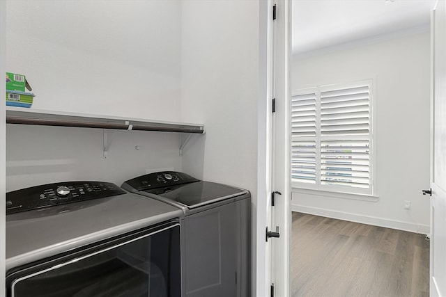 clothes washing area with separate washer and dryer, hardwood / wood-style flooring, and crown molding