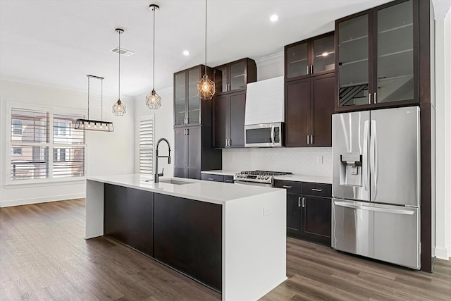 kitchen featuring stainless steel appliances, decorative backsplash, sink, a center island with sink, and dark hardwood / wood-style floors