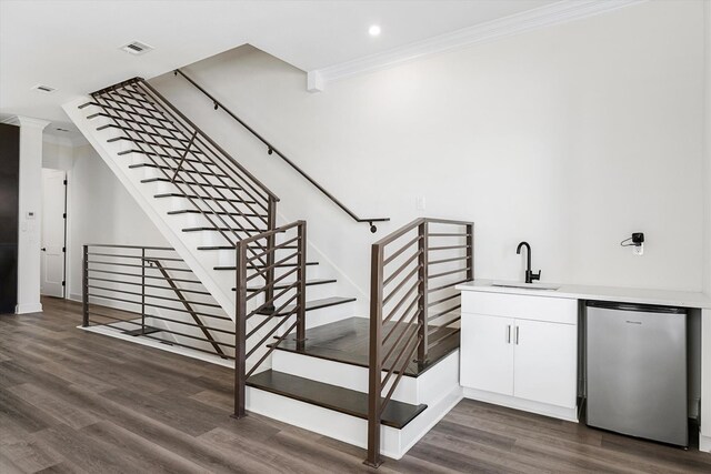 stairway with sink, hardwood / wood-style flooring, and ornamental molding