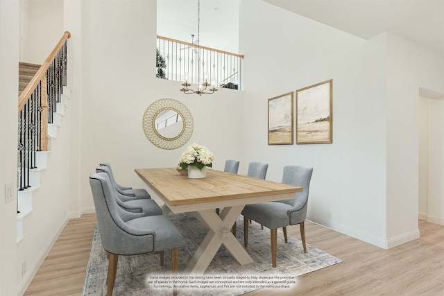 dining space with a chandelier, light hardwood / wood-style flooring, and a high ceiling