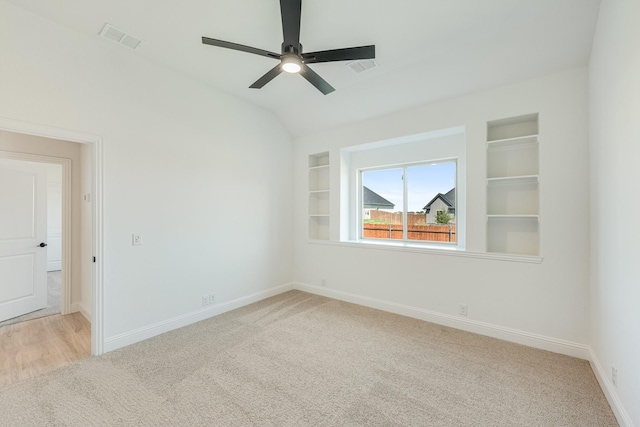 carpeted empty room featuring baseboards, a ceiling fan, built in shelves, and visible vents