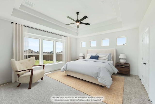 bedroom with visible vents, light carpet, baseboards, a raised ceiling, and a ceiling fan