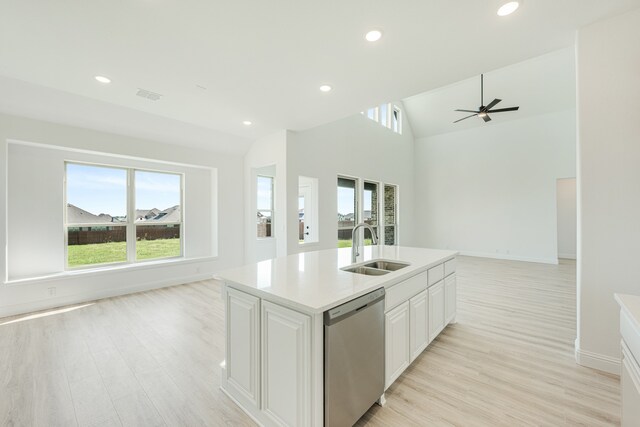 kitchen with sink, dishwasher, lofted ceiling, white cabinets, and light hardwood / wood-style flooring