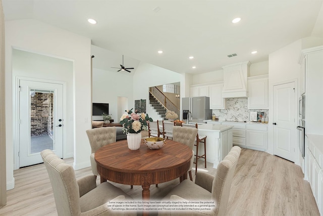 dining area featuring sink, light hardwood / wood-style floors, vaulted ceiling, and ceiling fan