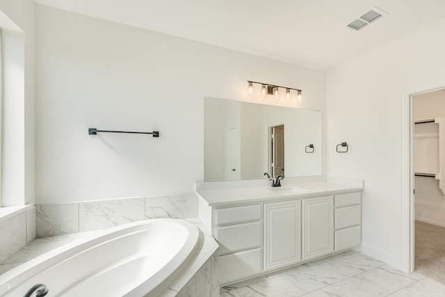 bathroom with vanity and tiled tub