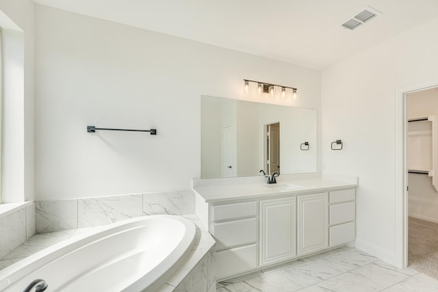 bathroom with a bath, visible vents, vanity, marble finish floor, and a spacious closet