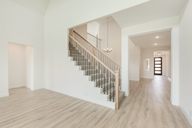 staircase with a notable chandelier, high vaulted ceiling, and hardwood / wood-style floors