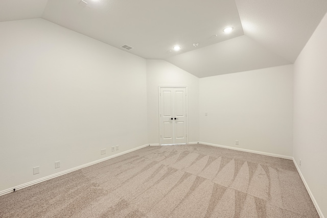 carpeted spare room with vaulted ceiling