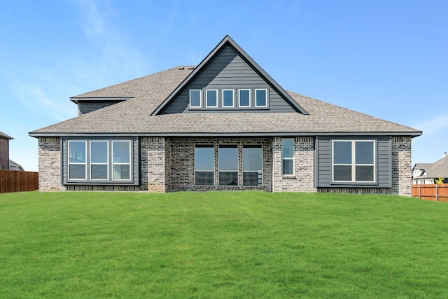 rear view of house featuring fence, a yard, and roof with shingles