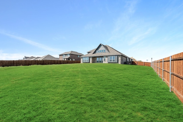 rear view of property featuring a fenced backyard and a yard