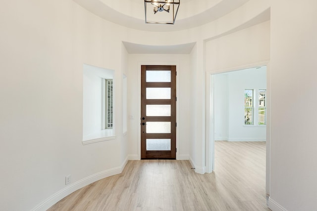 foyer entrance featuring baseboards, an inviting chandelier, and light wood-type flooring
