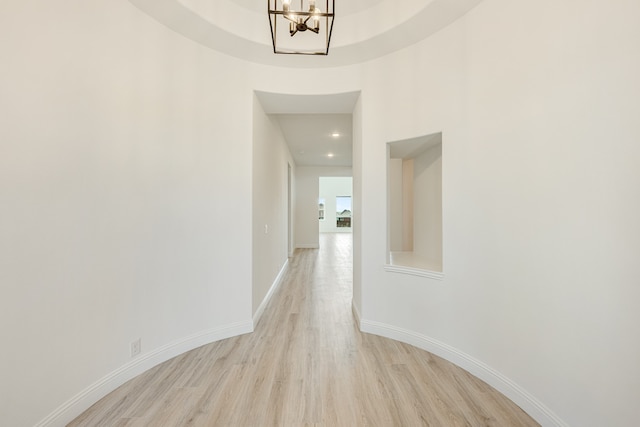 corridor with light hardwood / wood-style flooring and a notable chandelier