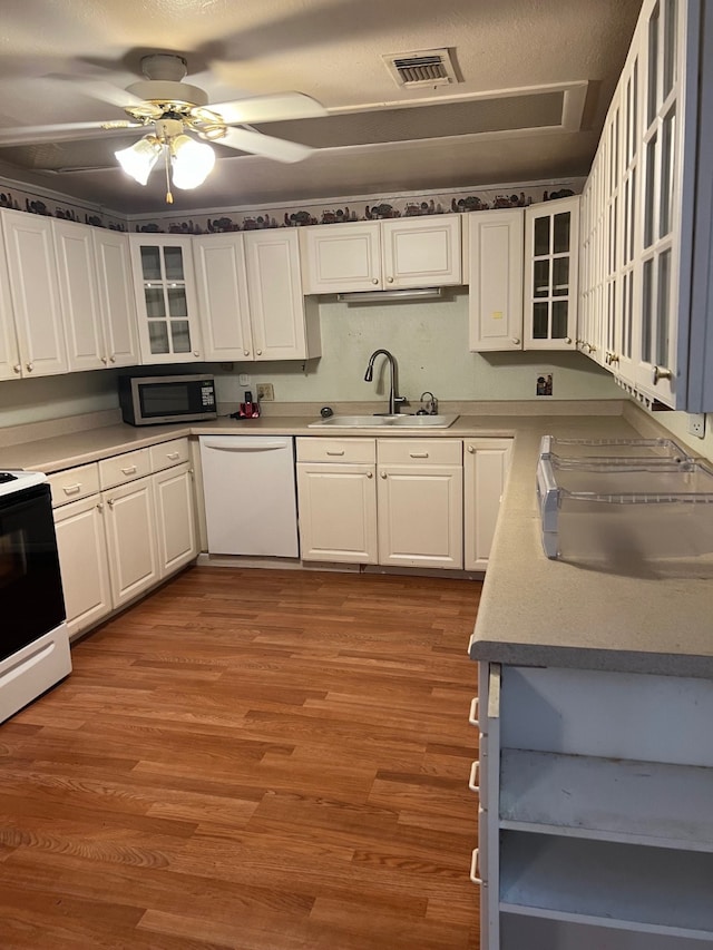 kitchen with white appliances, hardwood / wood-style floors, white cabinets, ceiling fan, and sink