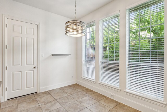 unfurnished dining area with light tile patterned floors and a notable chandelier