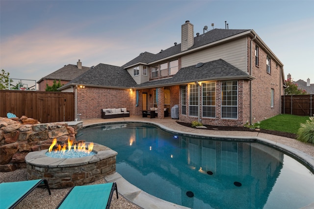 pool at dusk featuring a patio and a fire pit