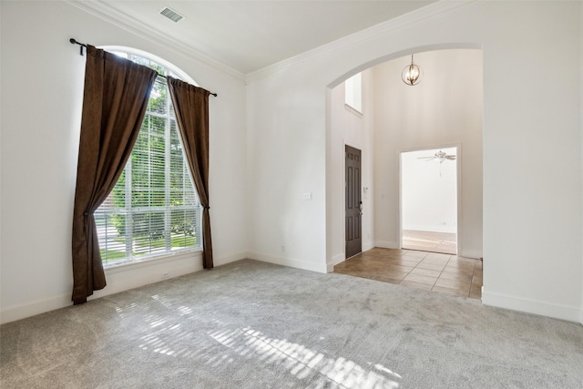 carpeted empty room with crown molding, plenty of natural light, and ceiling fan with notable chandelier