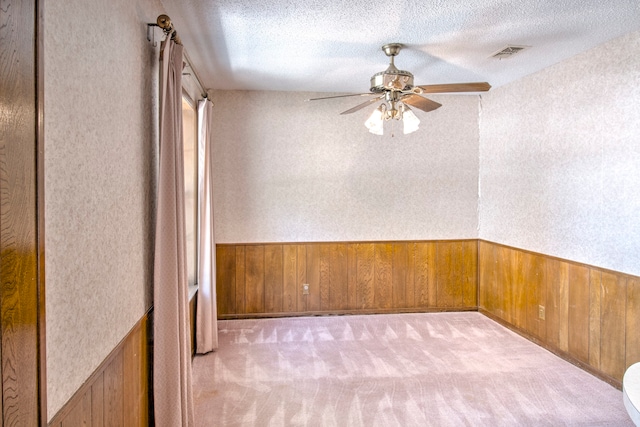 carpeted empty room with a textured ceiling and ceiling fan