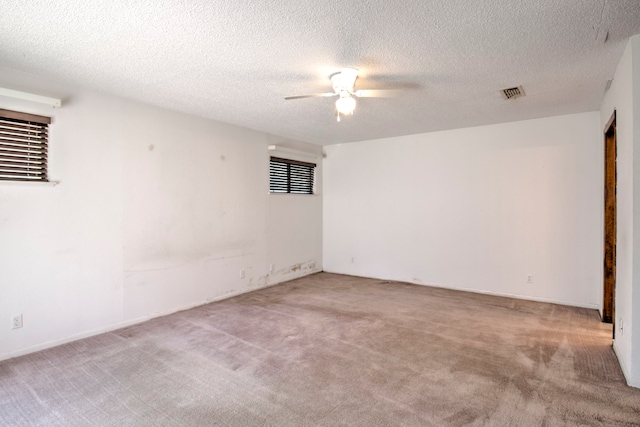 carpeted spare room featuring a textured ceiling and ceiling fan