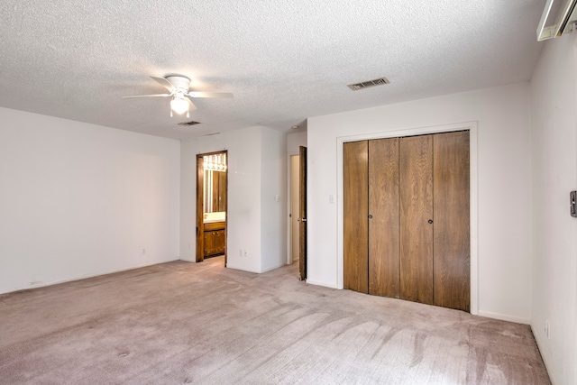 unfurnished bedroom with a textured ceiling, light colored carpet, a closet, and ceiling fan