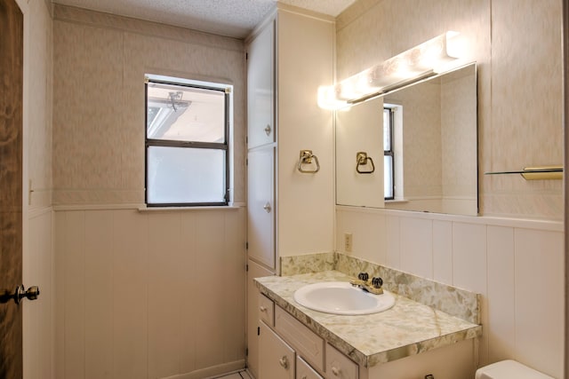 bathroom featuring vanity, a textured ceiling, toilet, and a healthy amount of sunlight