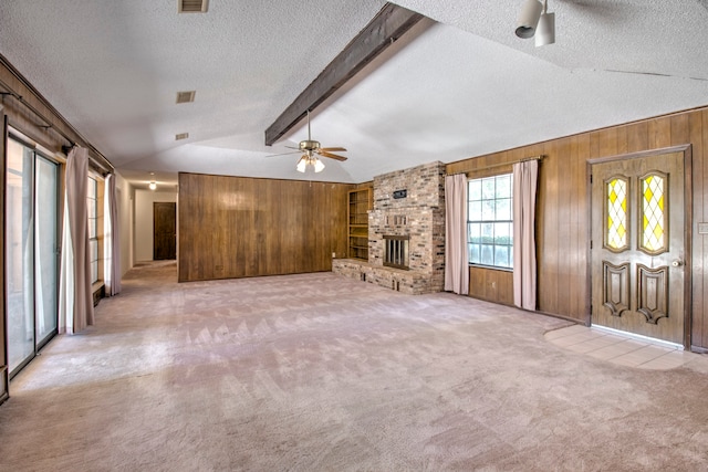 unfurnished living room featuring light carpet, a brick fireplace, ceiling fan, and vaulted ceiling with beams