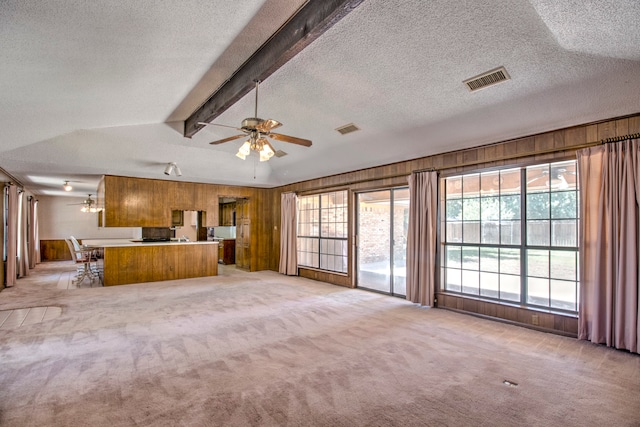 unfurnished living room featuring beamed ceiling, a textured ceiling, ceiling fan, and light colored carpet