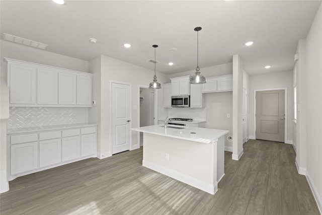 kitchen featuring pendant lighting, sink, a kitchen island with sink, and white cabinets