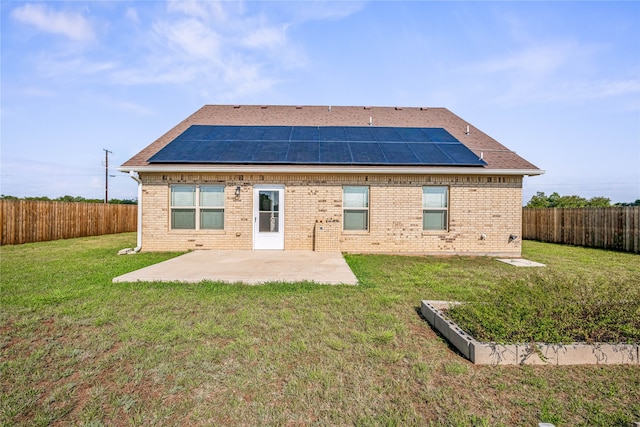 rear view of house with a patio area, a lawn, and solar panels