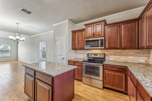 kitchen featuring light wood-type flooring, ornamental molding, a chandelier, a center island, and appliances with stainless steel finishes