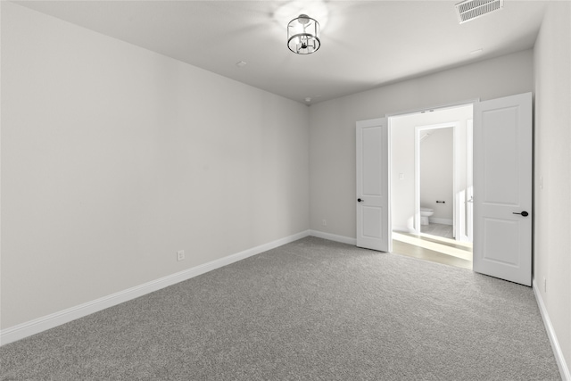 unfurnished bedroom featuring ensuite bathroom and carpet flooring