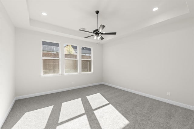 unfurnished room with ceiling fan, carpet floors, and a raised ceiling