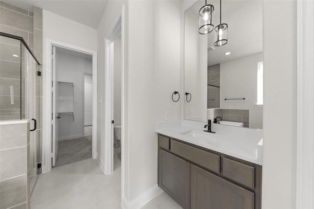 bathroom with walk in shower, vanity, tile patterned flooring, and toilet