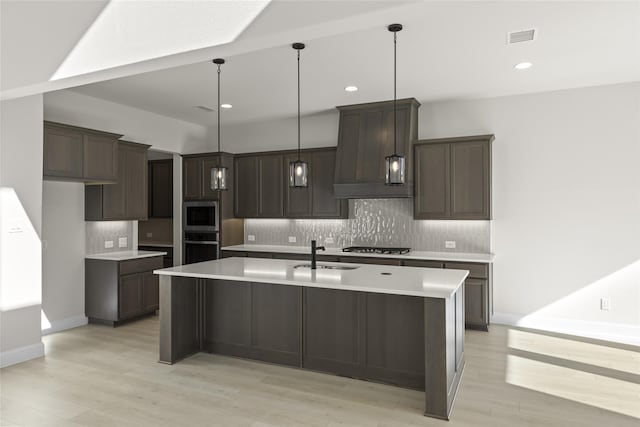 kitchen featuring sink, backsplash, an island with sink, and stainless steel appliances