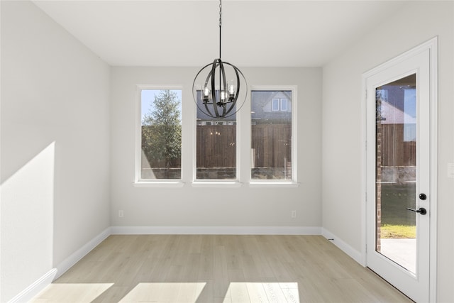 unfurnished dining area with a chandelier and light hardwood / wood-style flooring