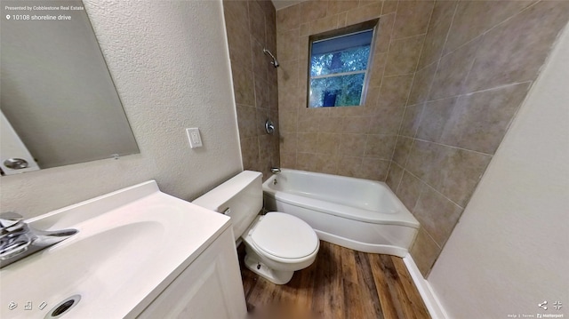 full bathroom with toilet, vanity, wood-type flooring, and tiled shower / bath