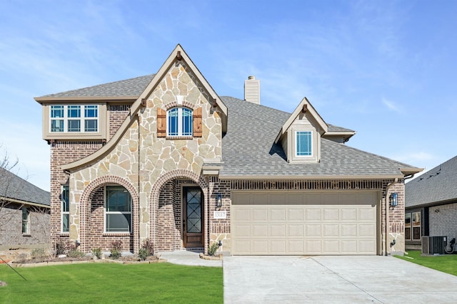 english style home with central AC unit, a garage, and a front yard