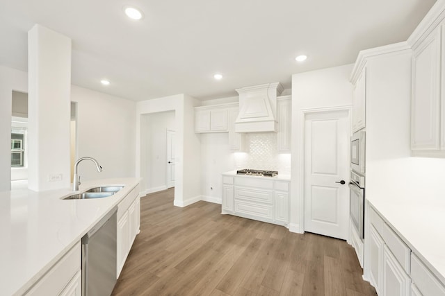 kitchen featuring white cabinetry, stainless steel appliances, sink, and custom range hood