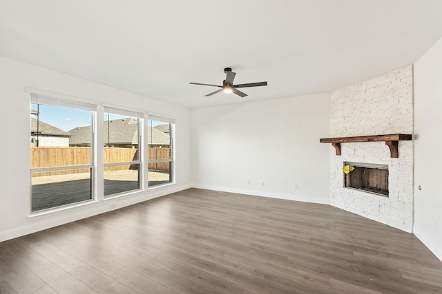 unfurnished living room featuring ceiling fan, a fireplace, and dark hardwood / wood-style flooring