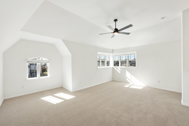 unfurnished living room featuring ceiling fan, light colored carpet, a healthy amount of sunlight, and lofted ceiling