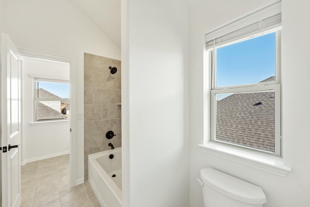 bathroom with tiled shower / bath combo, vaulted ceiling, tile patterned floors, and toilet