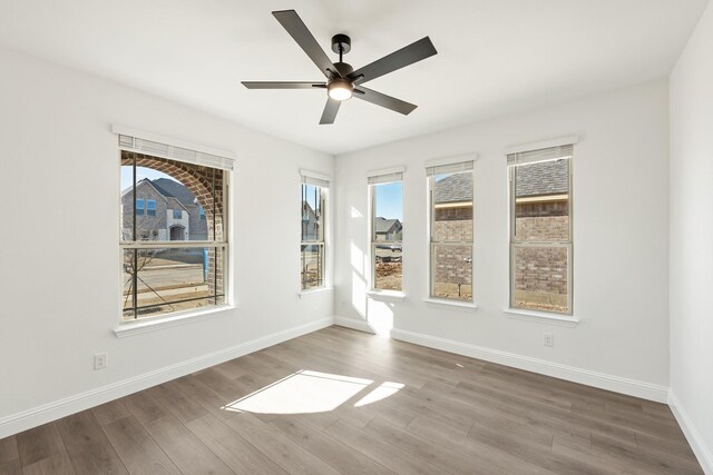 unfurnished room with ceiling fan, plenty of natural light, and wood-type flooring