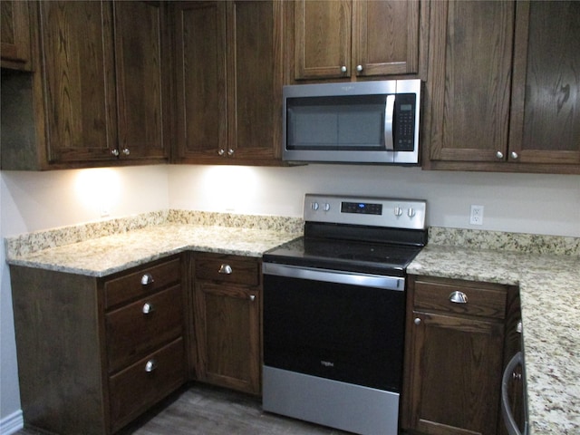 kitchen with light stone countertops, appliances with stainless steel finishes, and dark brown cabinetry