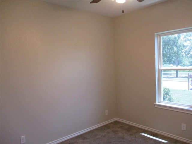 spare room featuring ceiling fan, a healthy amount of sunlight, and dark colored carpet