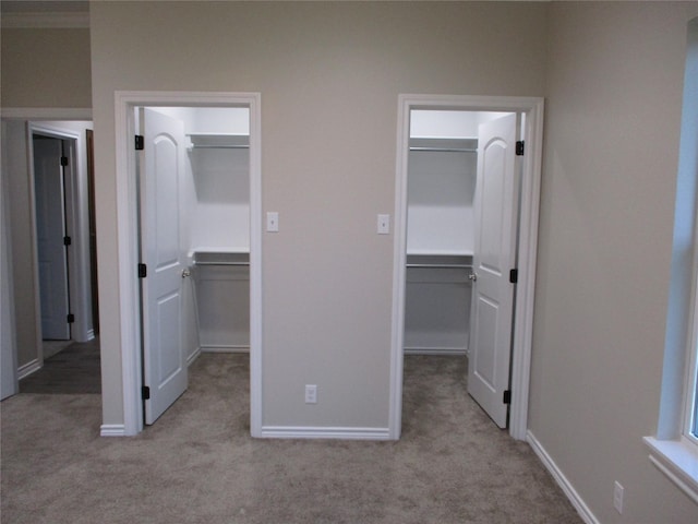 unfurnished bedroom with crown molding, ensuite bathroom, a spacious closet, light colored carpet, and a closet