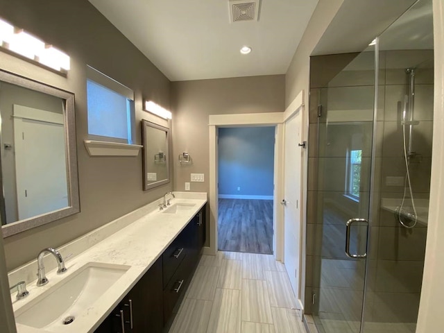 bathroom with an enclosed shower, hardwood / wood-style floors, and dual bowl vanity