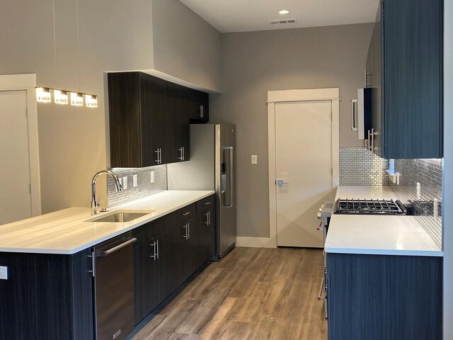 kitchen featuring sink, dishwashing machine, tasteful backsplash, and light wood-type flooring